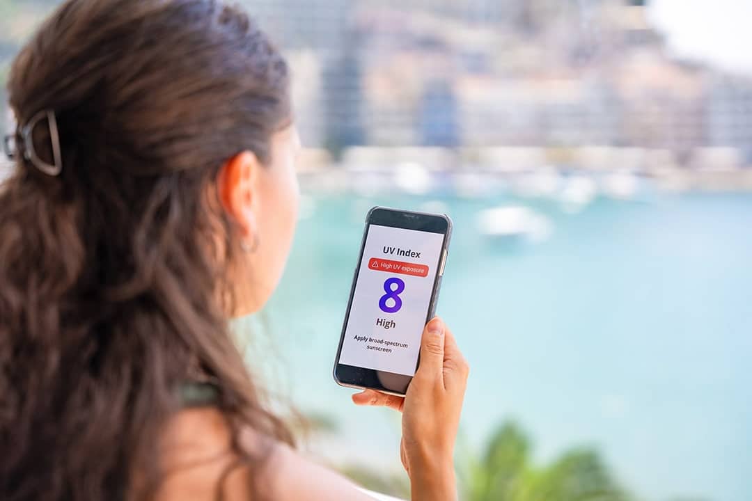 A woman checking the UV index forecast on her phone.